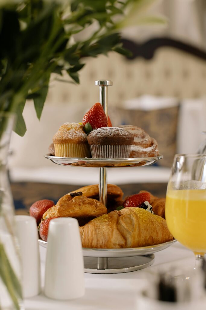 Luxurious breakfast setup with croissants, muffins, and orange juice on a serving tray.